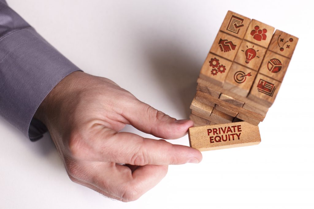 Hand pulling a wooden block labeled Private Equity from a stack of blocks with business icons