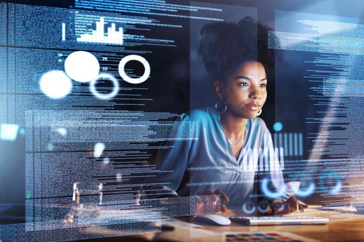 Professional working at a computer at night behind transparent screens of data, charts and document text